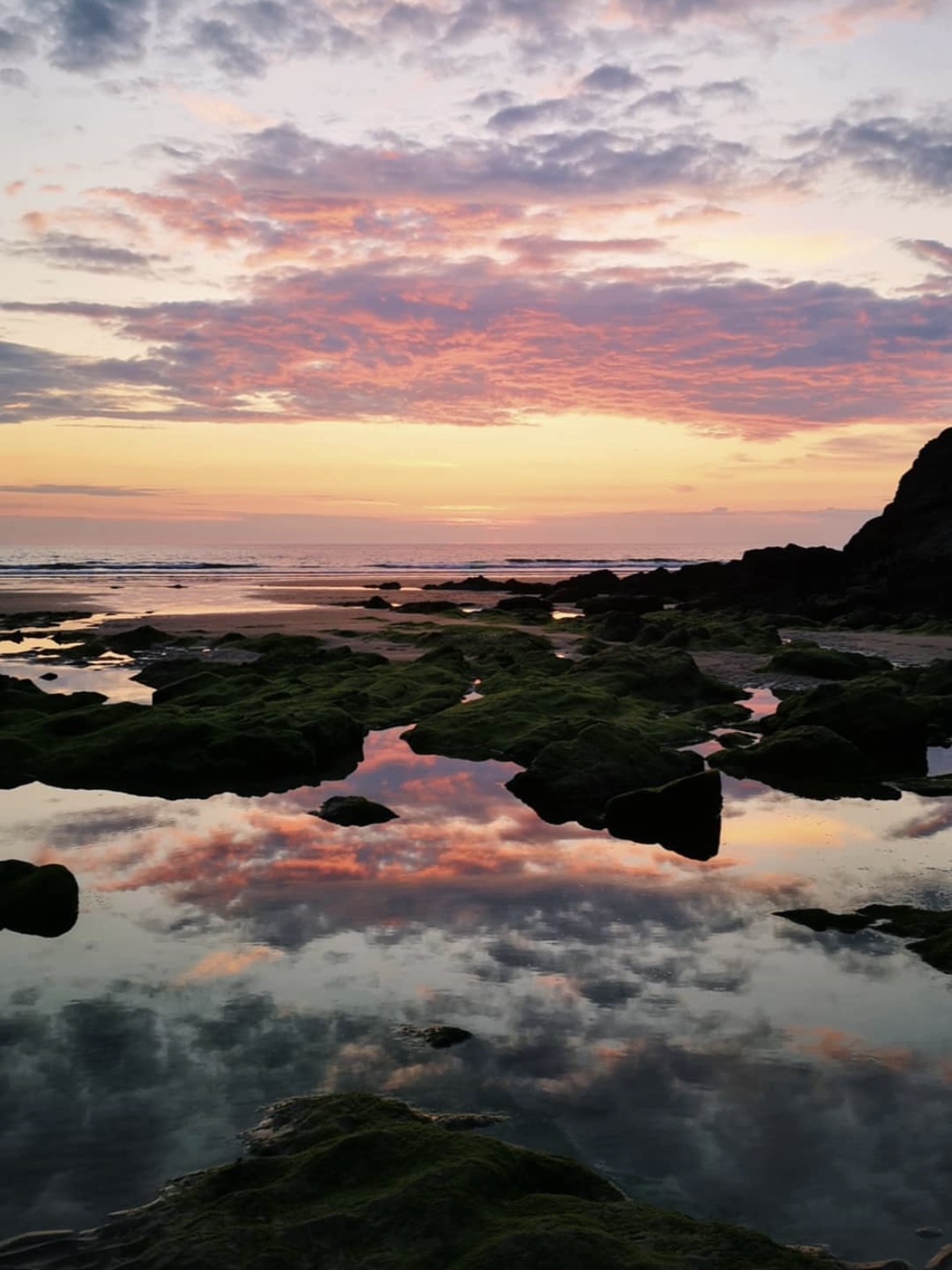 Sunset over a Cornish beach with golden sand and gentle waves, evoking the coastal inspiration behind Sadie Jewellery designs